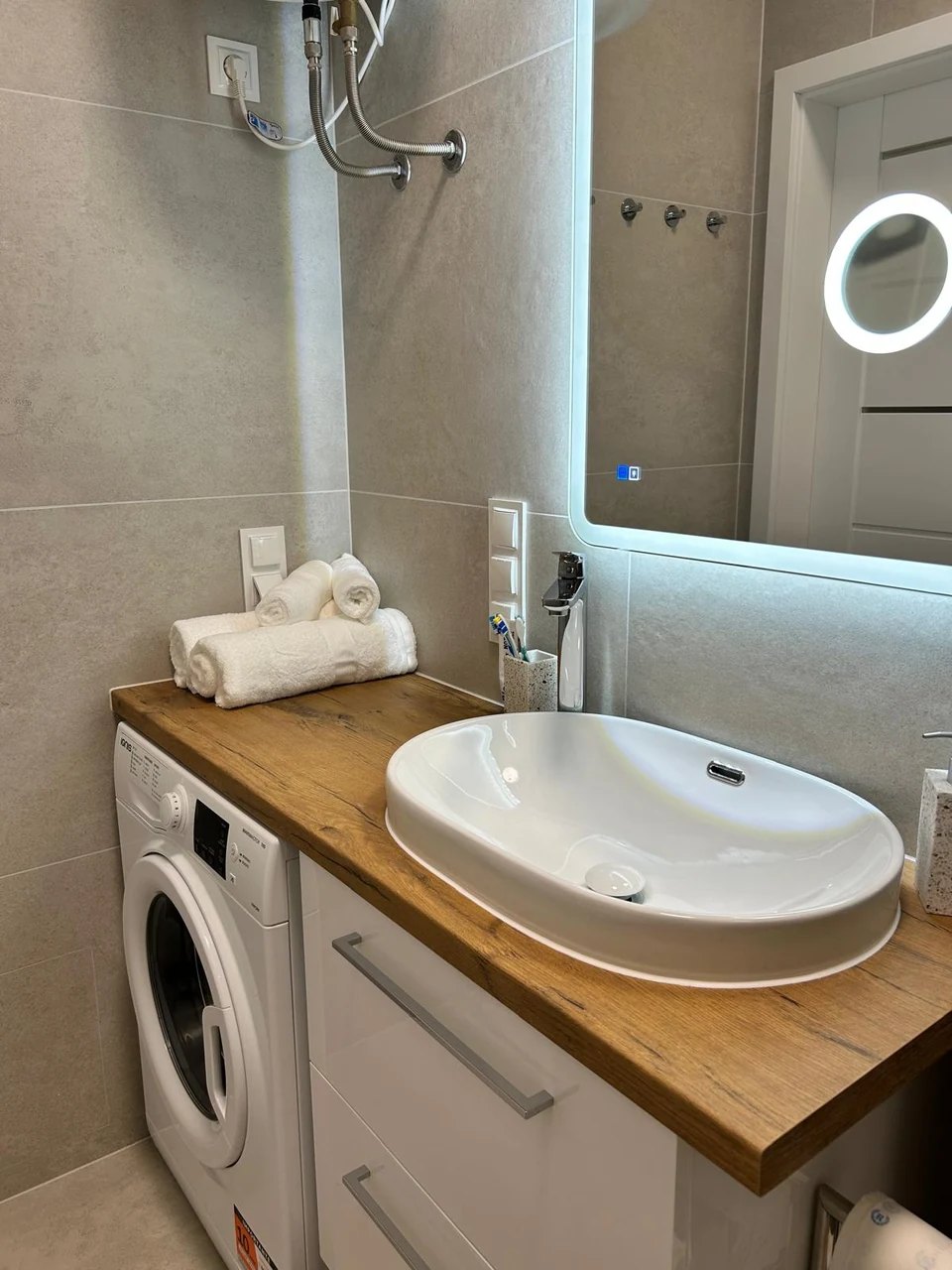 The washbasin on a wooden top with the washing machine below